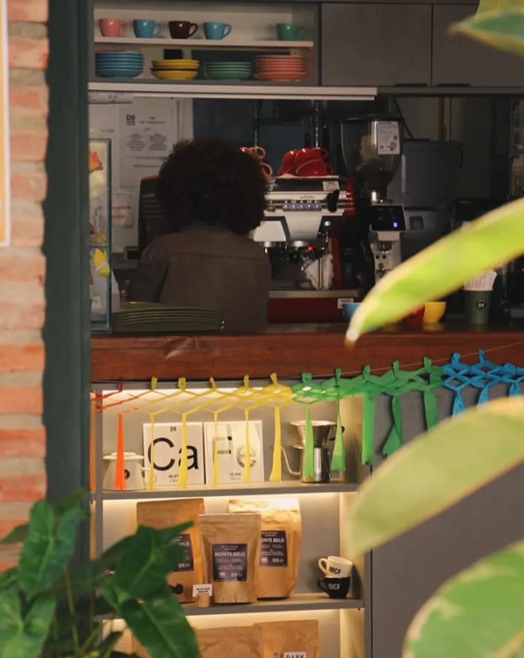 Balcão visto por entre folhas, com o letreiro CaFe