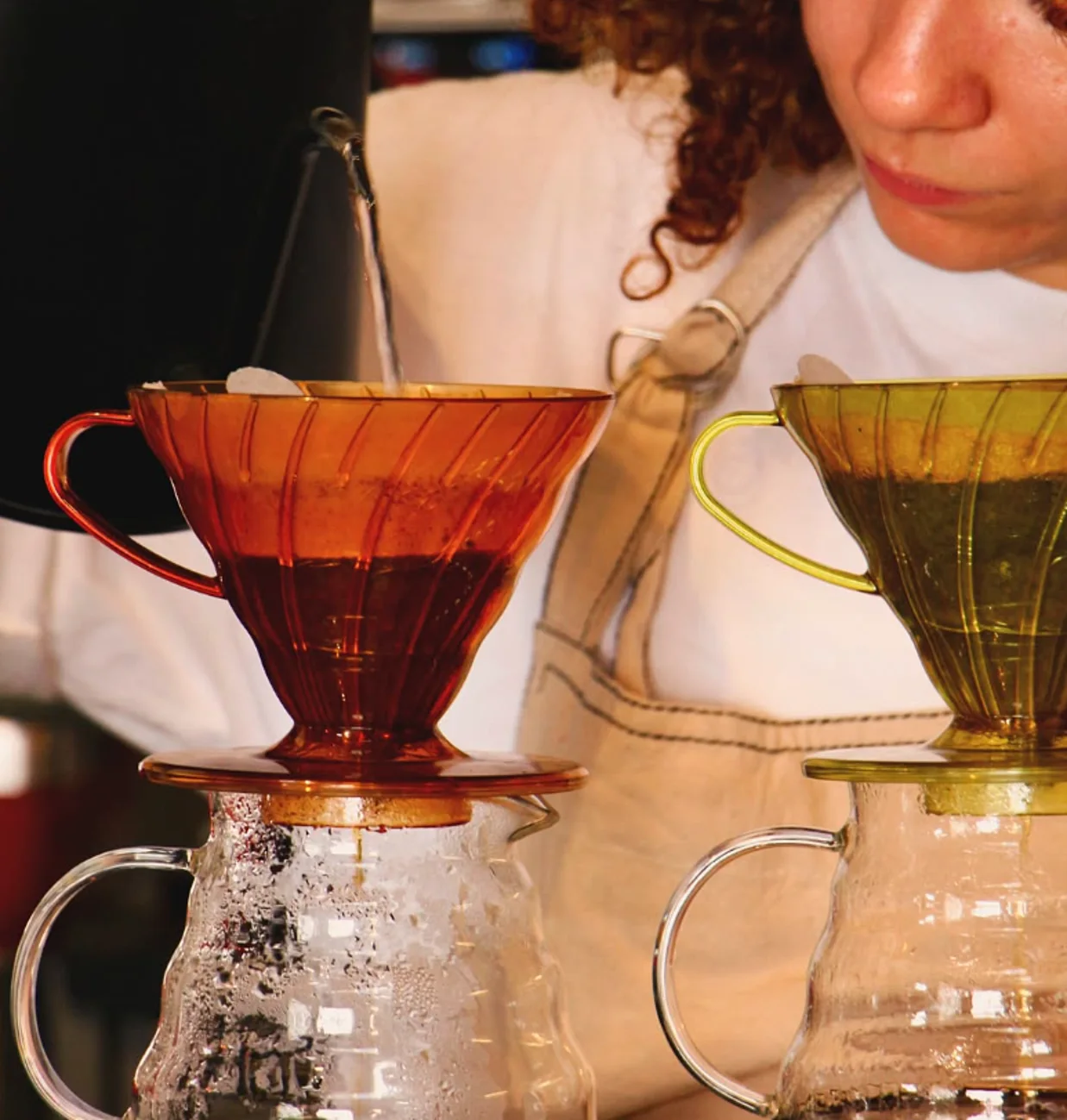 Barista preparando café coado em dois V60, âmbar e verde