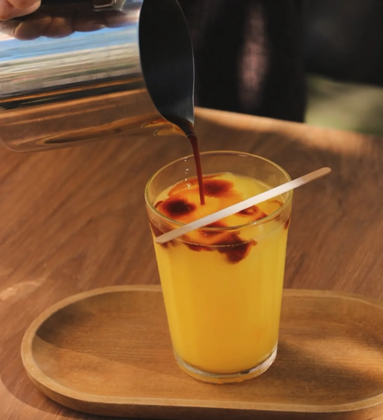 Espresso sendo vertido sobre suco de laranja