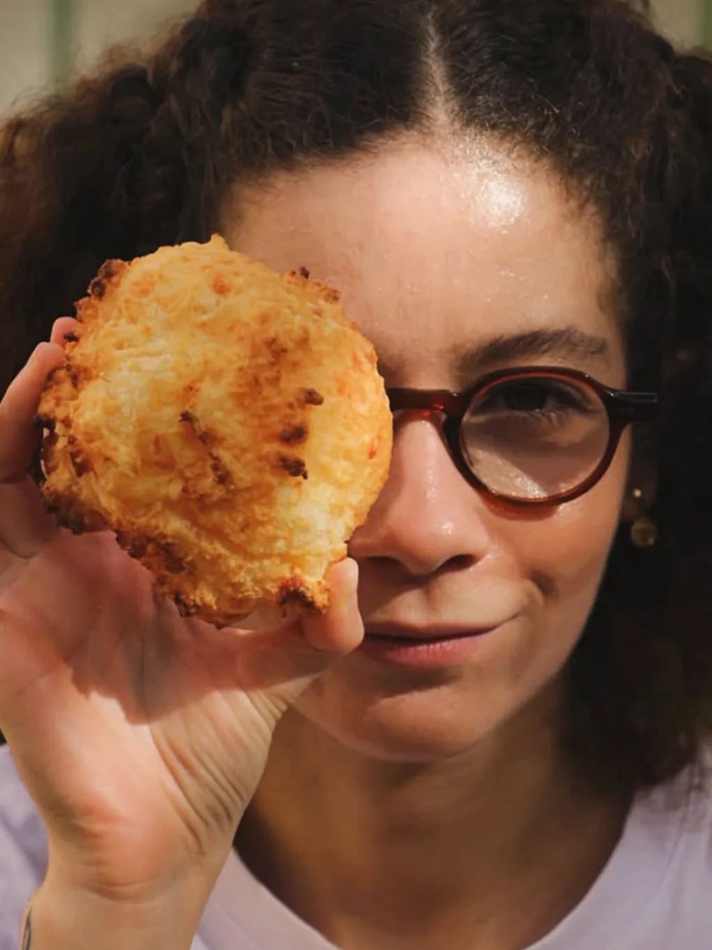 Mulher de óculos segurando um biscoito na frente do olho